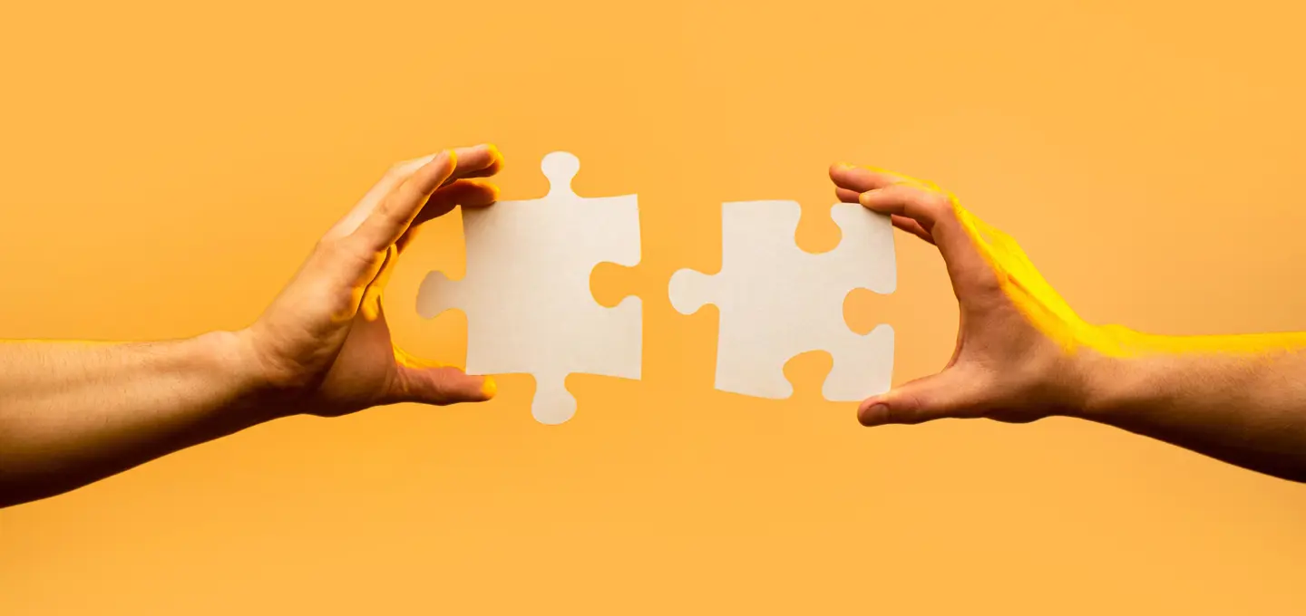 Two hands putting two puzzle pieces together