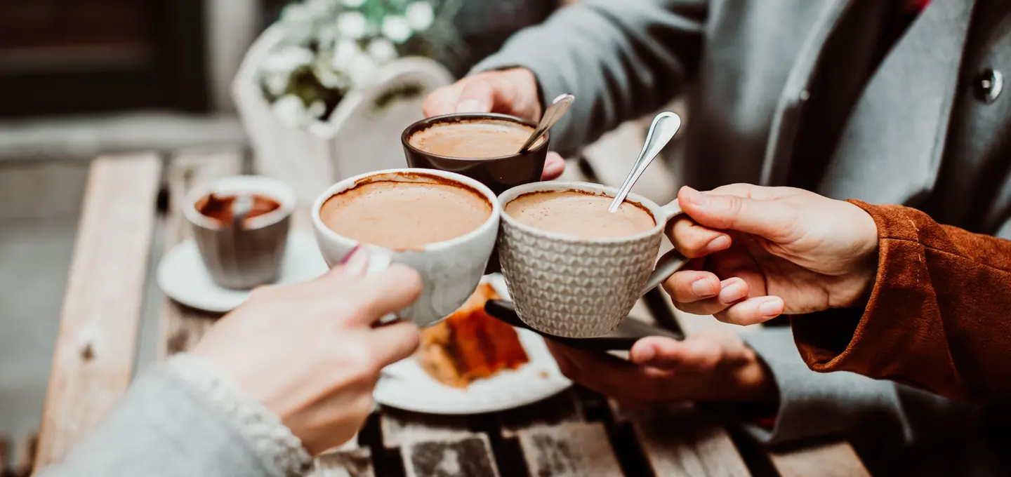 Three people toasting together with a coffee