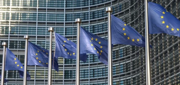 Reihe von wehenden EU-Flaggen vor einem modernen Glasgebäude