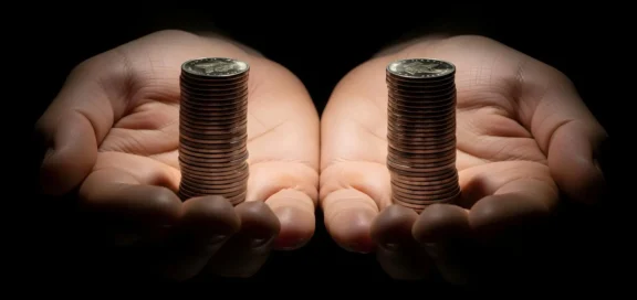 Zwei Hände halten jeweils einen Stapel Münzen gleicher Höhe als Symbol für gleiche Bezahlung und Lohngerechtigkeit sowie für die EU-Richtlinie zur Lohntransparenz.