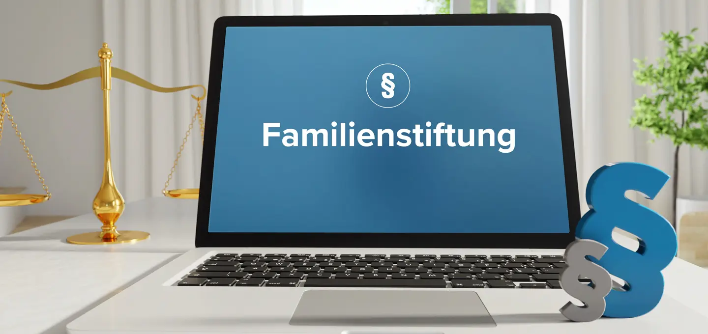 Laptop with the words “Family Foundation” on the screen, next to it a golden set of scales and a blue paragraph symbol representing legal issues. Symbolic of the new foundation register.