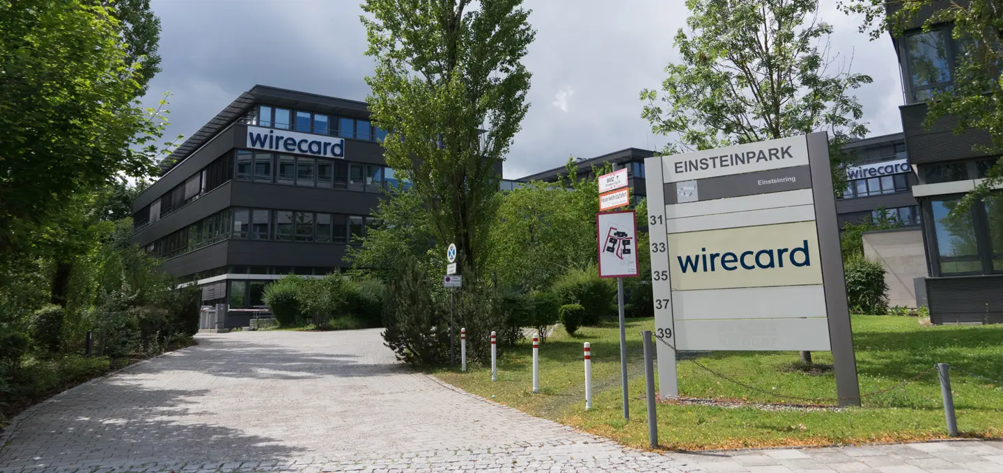 Office building of the former payment service provider Wirecard in Einsteinpark with the Wirecard logo visible on the façade and on a company sign in the foreground, surrounded by trees and green spaces. Federal Court of Justice confirms: Wirecard shareholders have no claim to the insolvency estate.