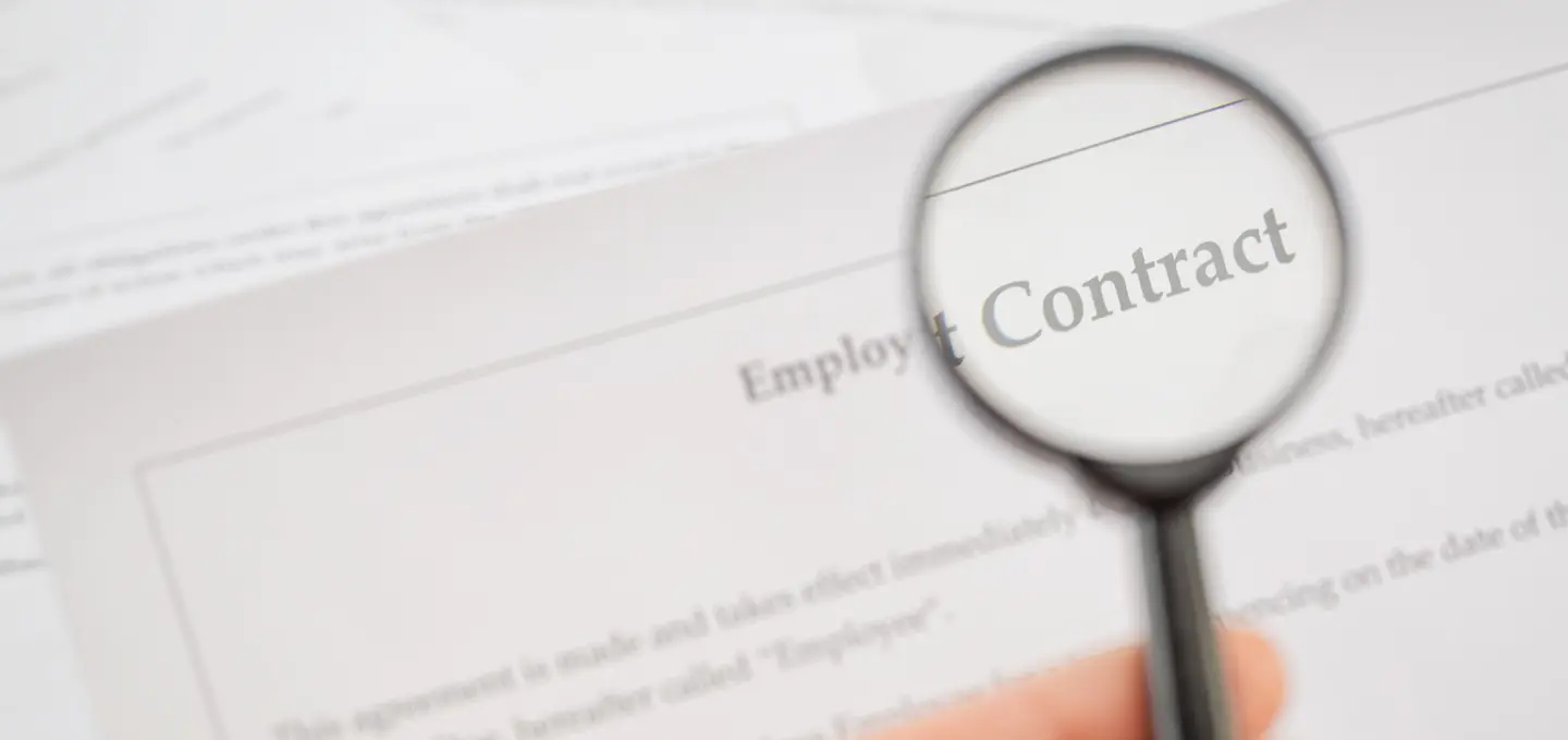 Magnifying glass over an employment contract – symbolic representation of the legal review of a reference clause in labour law.