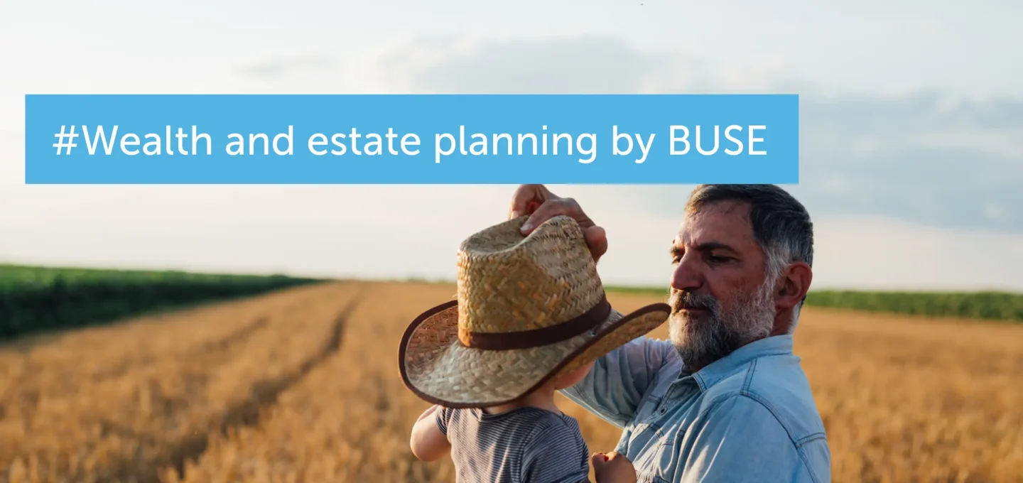 An elderly man puts a straw hat on a child's head in a field – a symbolic image for wealth and succession planning.