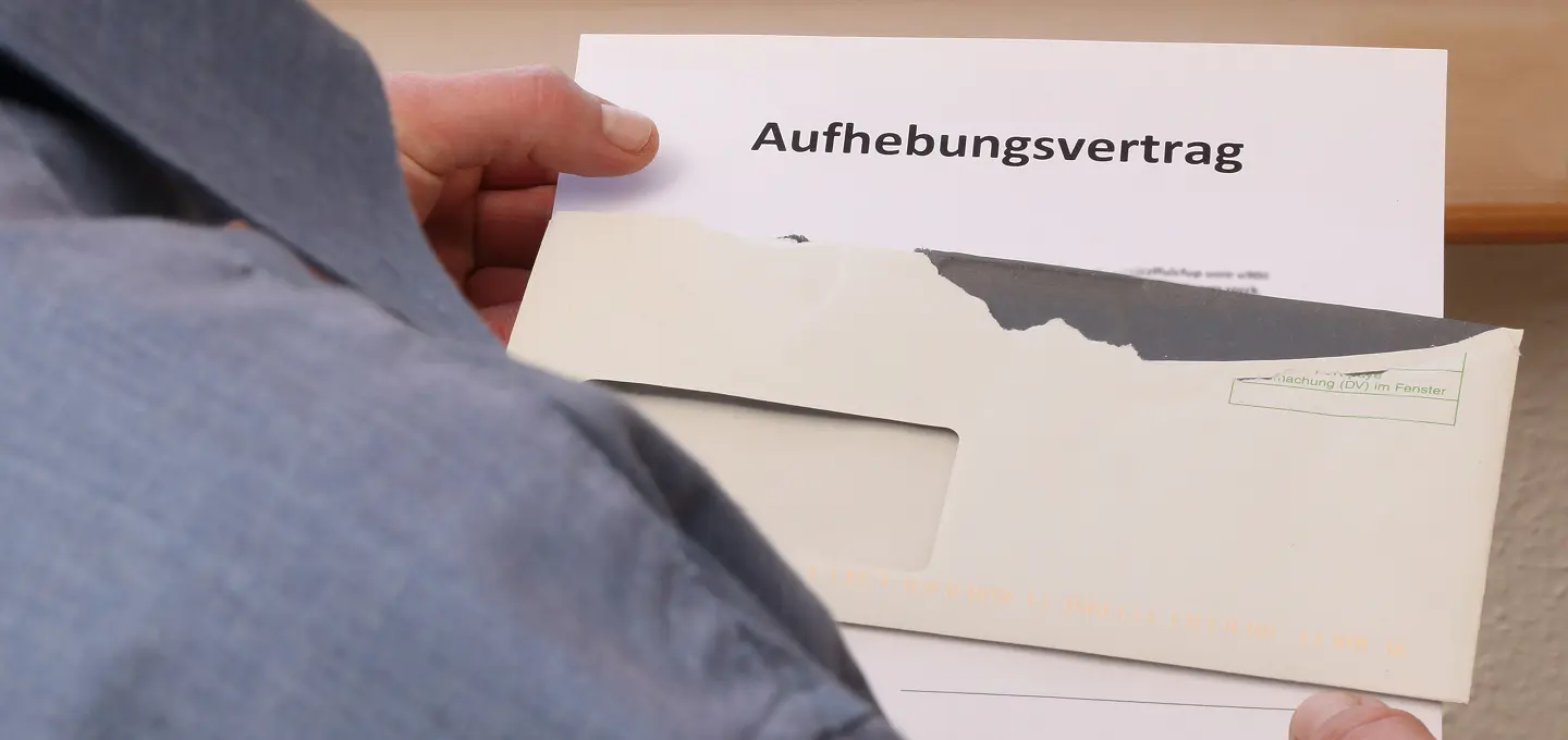 Person öffnet Brief mit Aufhebungsvertrag im Fensterumschlag – Besteuerung von Abfindungen