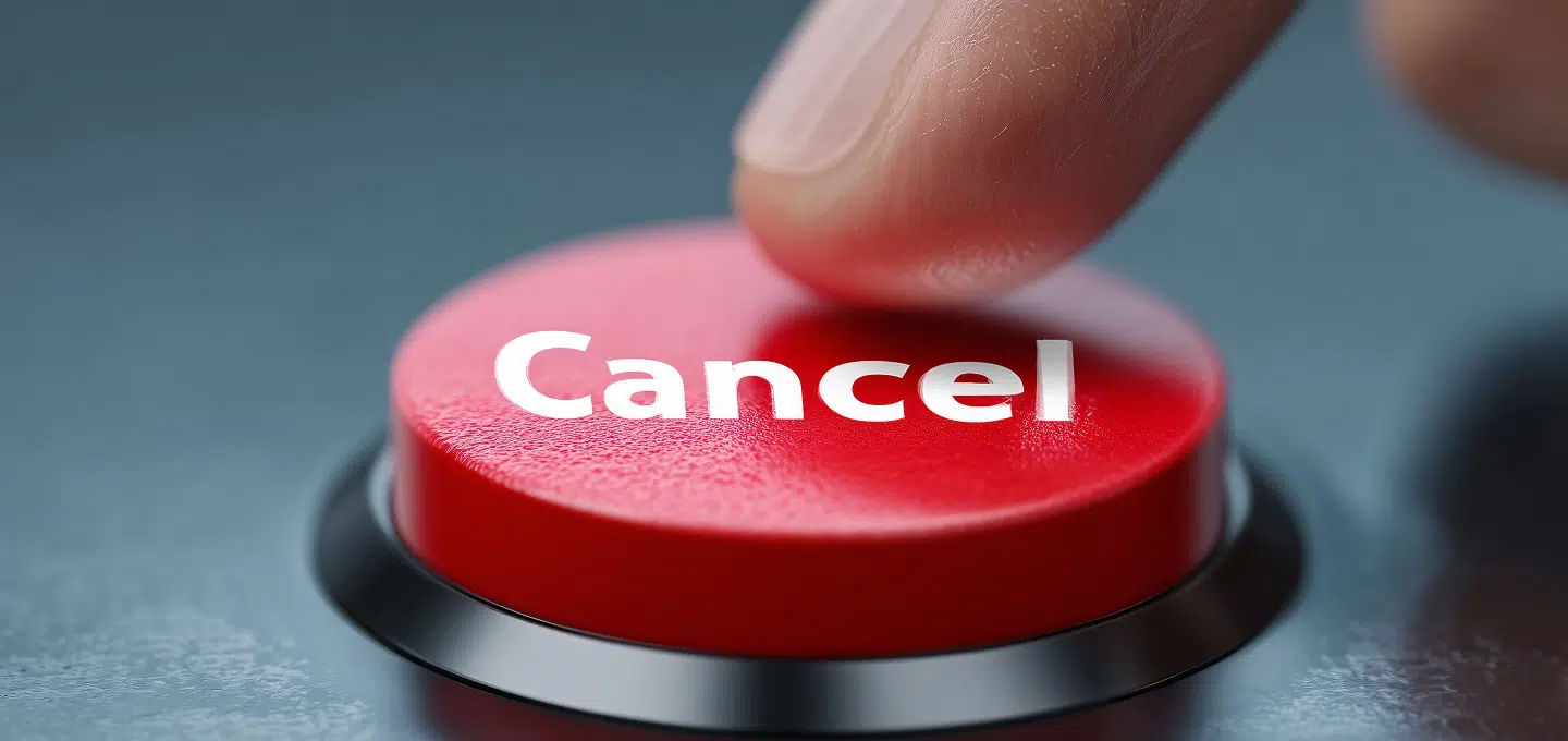Nahaufnahme eines roten Knopfes mit der Aufschrift „Cancel“, der von einem Finger gedrückt wird. Der Knopf ist in eine dunkle Oberfläche eingelassen, der Hintergrund ist unscharf. Das Bild symbolisiert die Widerrufsbelehrung zum Franchisevertrag
