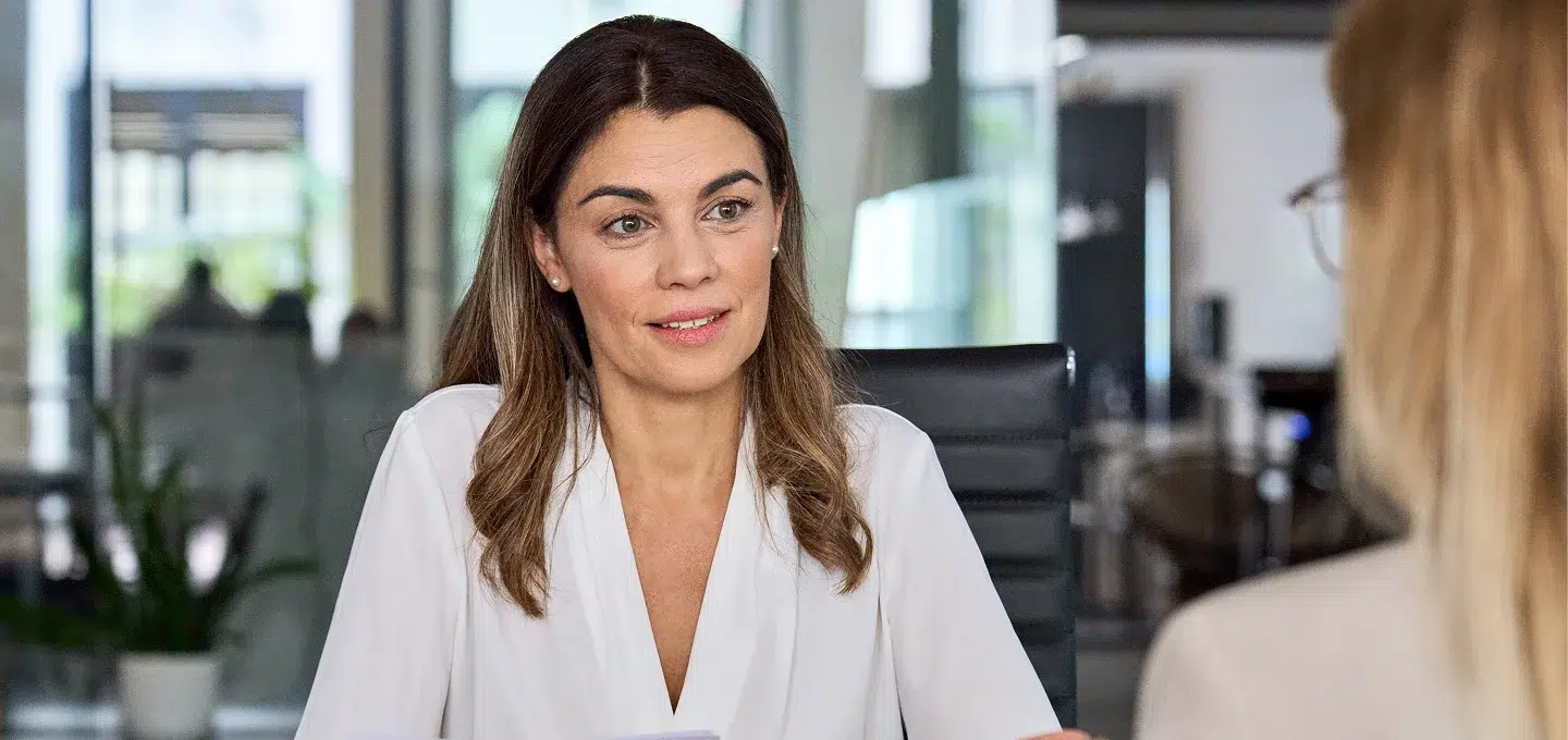 Frau im Business-Outfit im Gespräch mit Kollegin im Büro – Beratung zu Abfindung und Entgelttransparenzrichtlinie