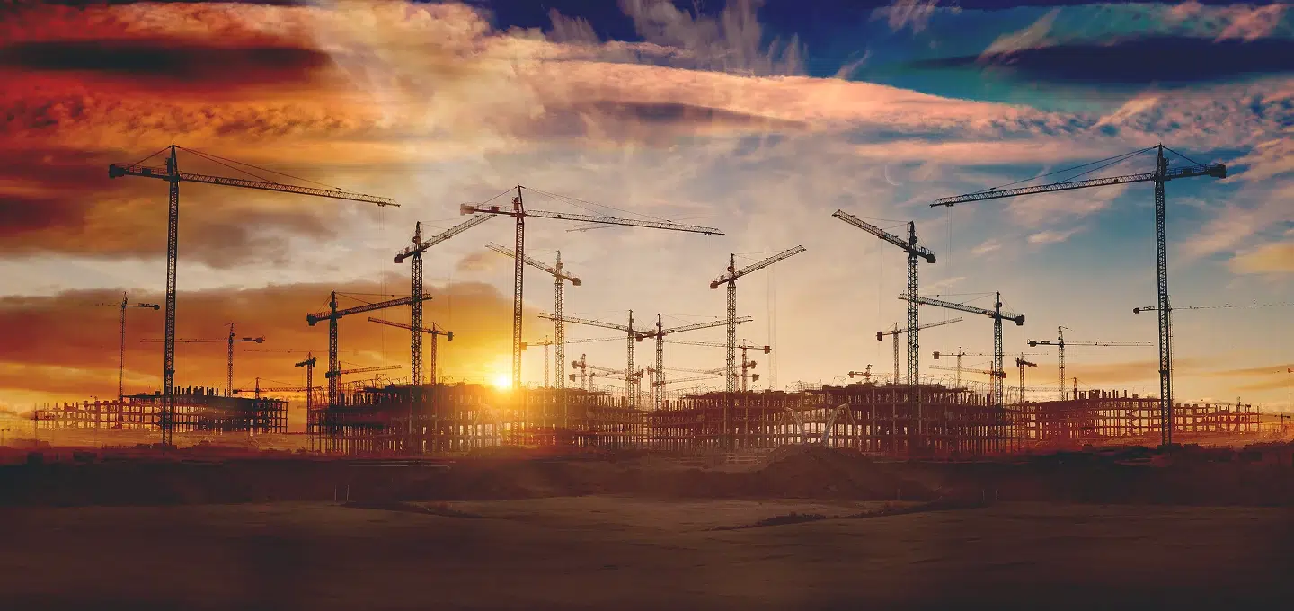 Baustelle mit mehreren Baukränen im Sonnenuntergang – Symbolbild zur Kündigungsvergütung im Bauvertragsrecht